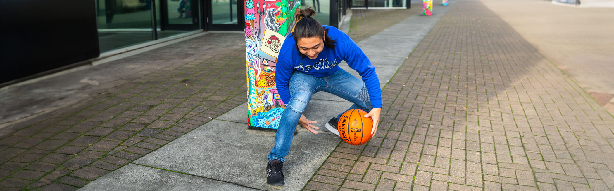 Man playing basketball on sidewalk