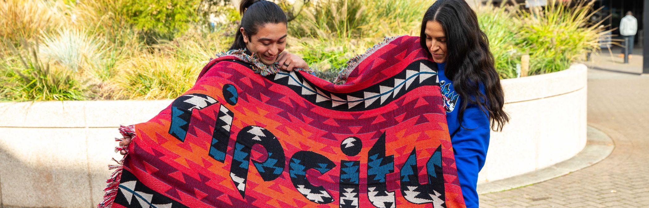 Eighth Generation Native Blanket x Trail Blazers held by two Native American models