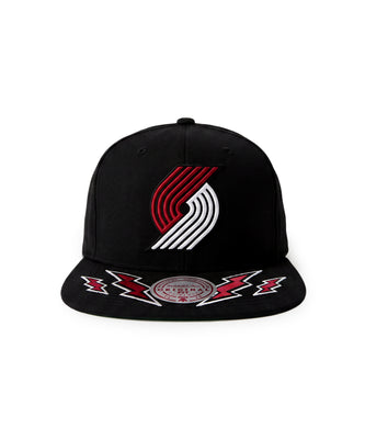 A black flat-brim snapback cap featuring the Portland Trail Blazers logo embroidered on the front in red and white, with red and white lightning bolt embroidery on the brim and a circular Mitchell & Ness brand patch.