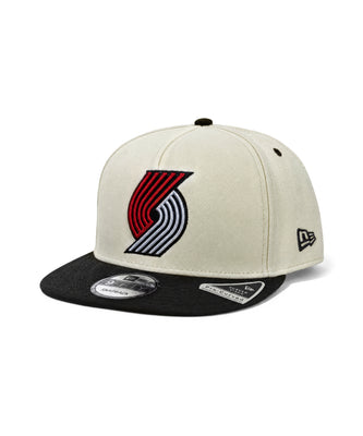 A Portland Trail Blazers New Era 9FIFTY snapback cap featuring an off-white crown with a black flat brim. The front displays the embroidered red, black, and white Blazers logo, and the New Era flag logo is visible on the side.
