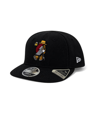 A black New Era 9FIFTY fitted baseball cap featuring a Portland Trail Blazers embroidered logo on the front, a white New Era flag logo on the side, and a silver metallic sticker on the brim, set against a plain white background.