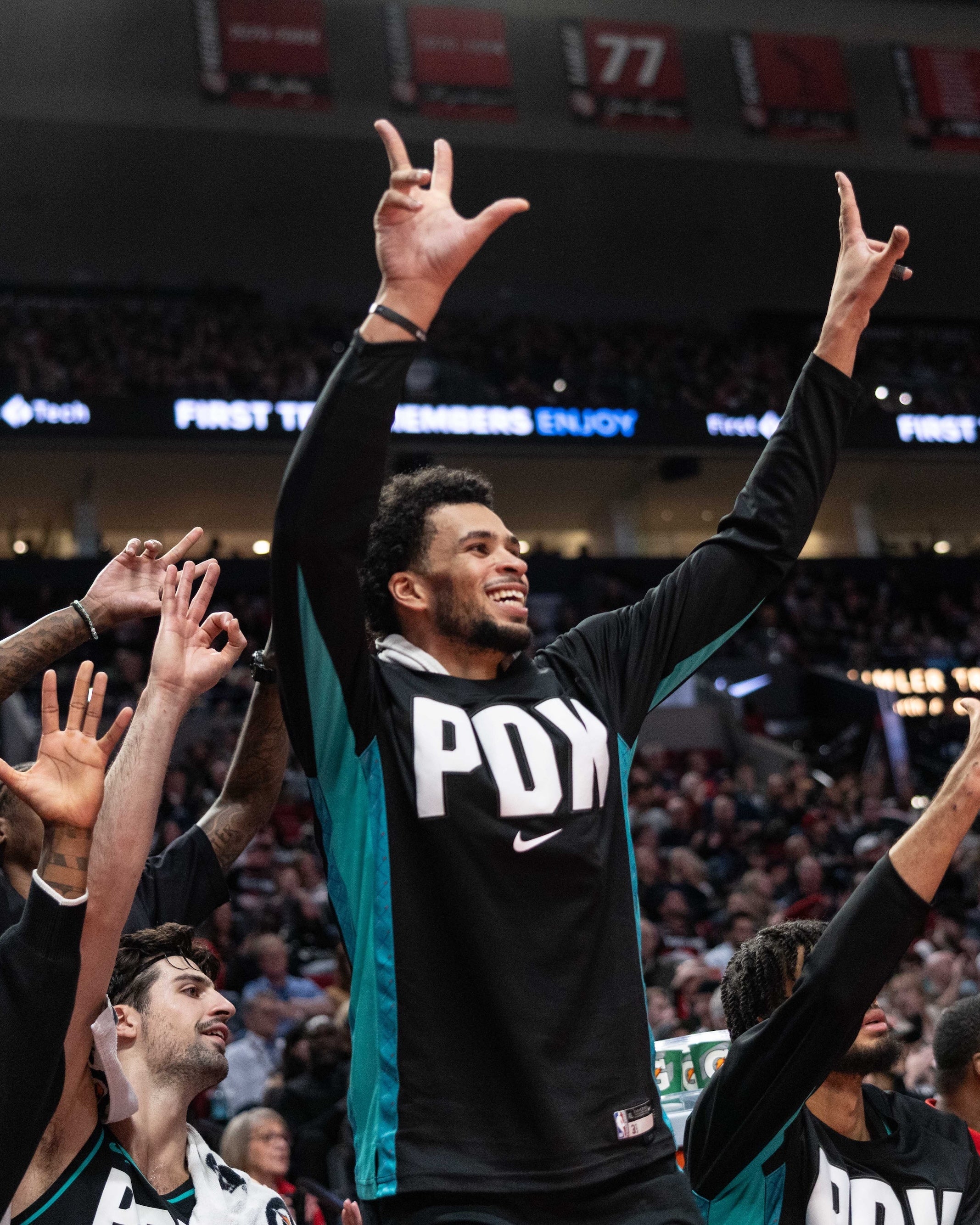 Basketball player in a black jersey with 'PDX' on it, celebrating in front of a crowd.