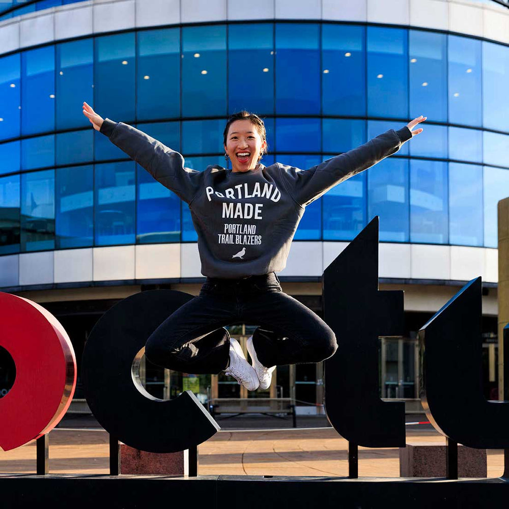 woman wearing staple and jumping in air in front of rip city sign at moda center